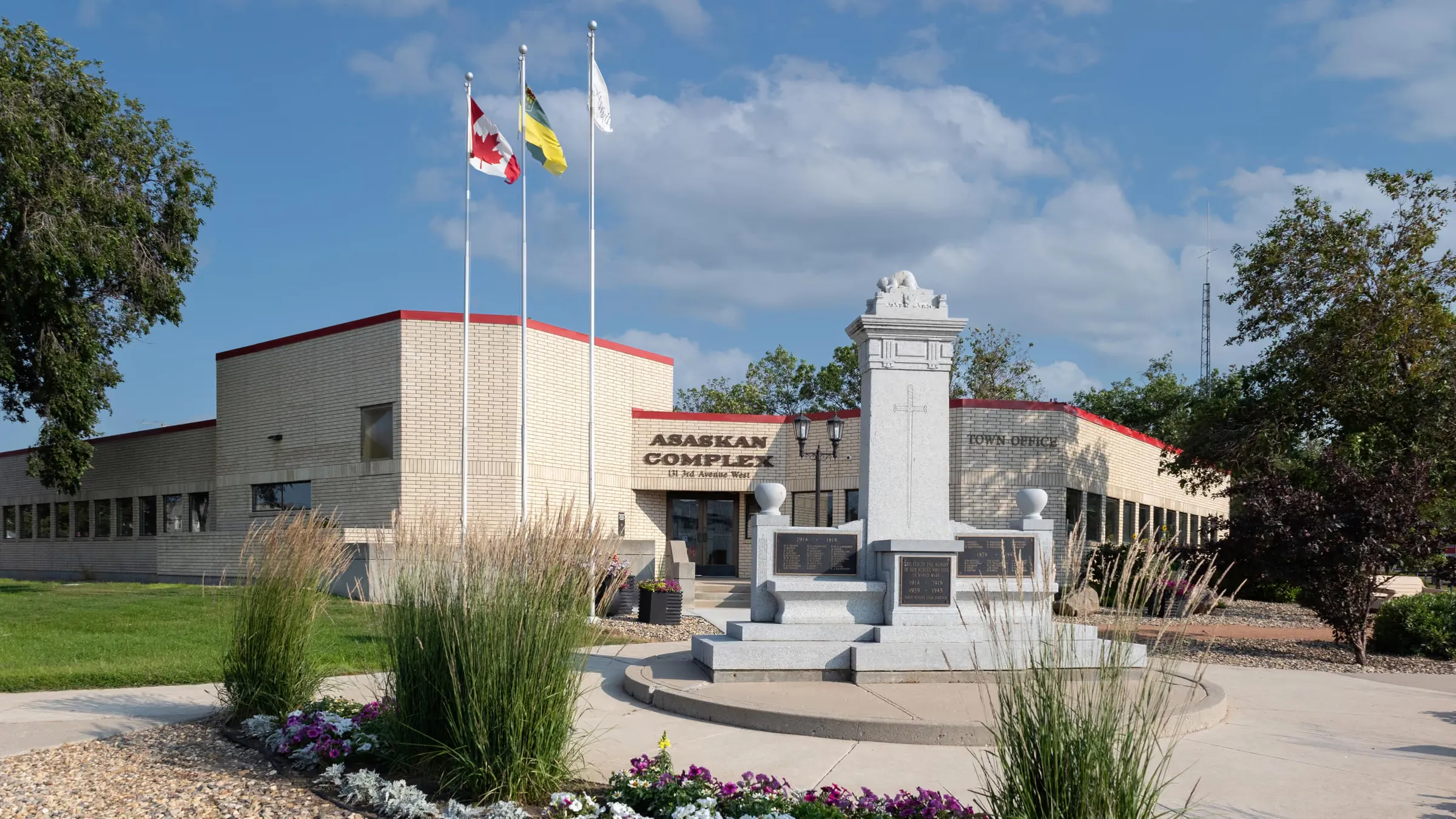 The Town Office in the Asaskan Complex at 131 3rd Avenue West, Assiniboia — cenotaph and flags out front