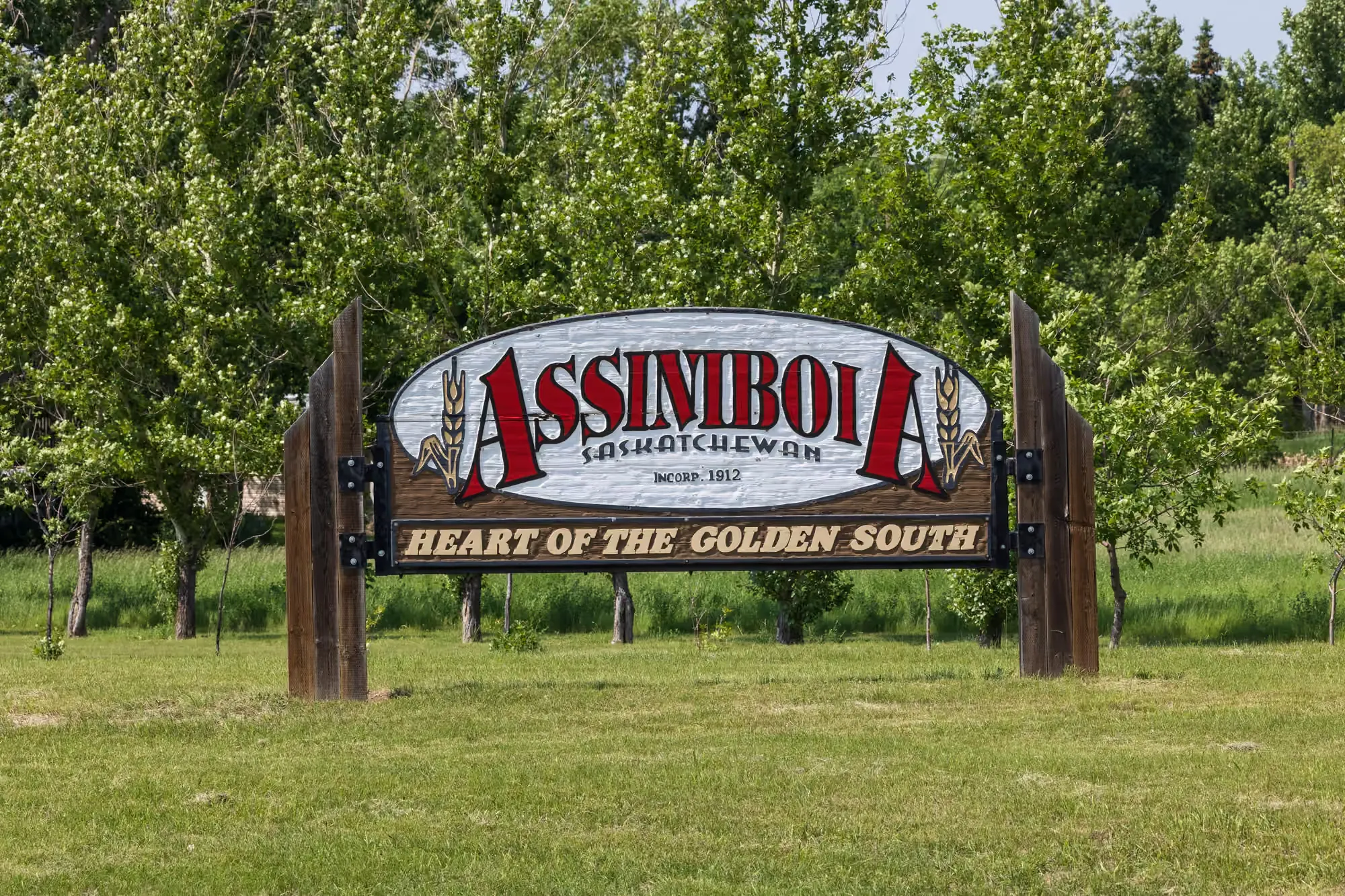 The Assiniboia welcome sign — Heart of the Golden South — flanked by wheat sheaves at the edge of town